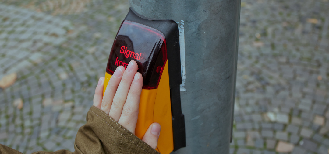 Eine Hand berührt den Sensor eines Ampeltasters